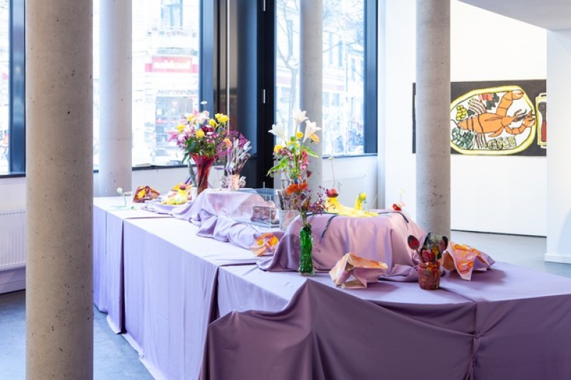 Gedeckter Tisch mit violetter Tischdecke und Blumensträußen